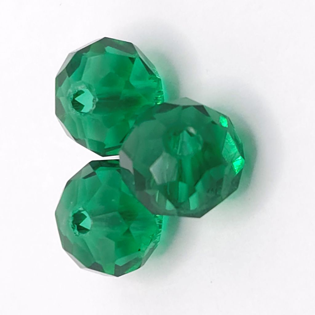 Three faceted green glass beads with a central hole, arranged on a plain white background.