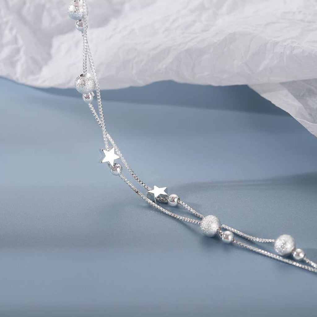 Silver beaded bracelet on a soft white fabric background