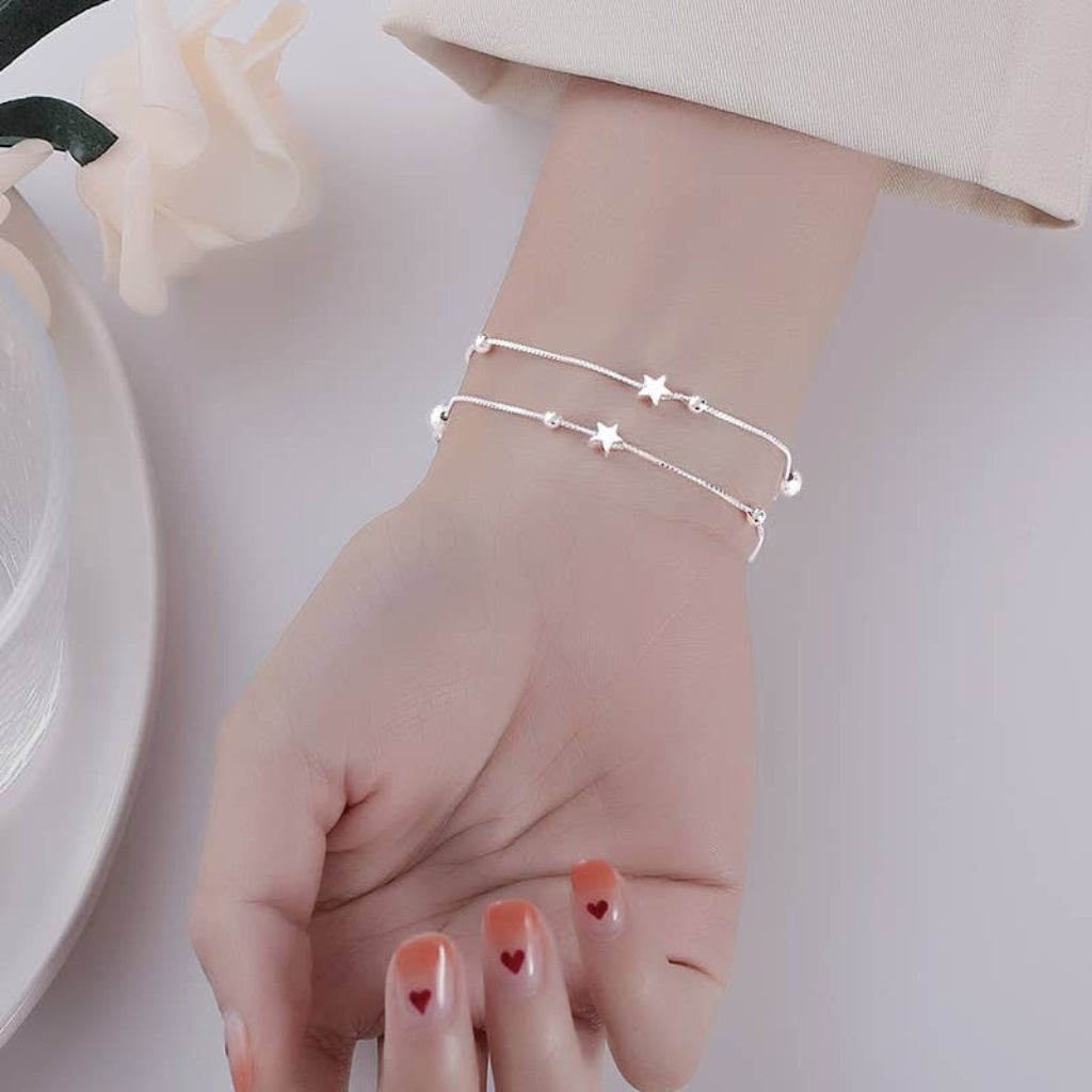 Silver bracelet on a wrist with a plain background