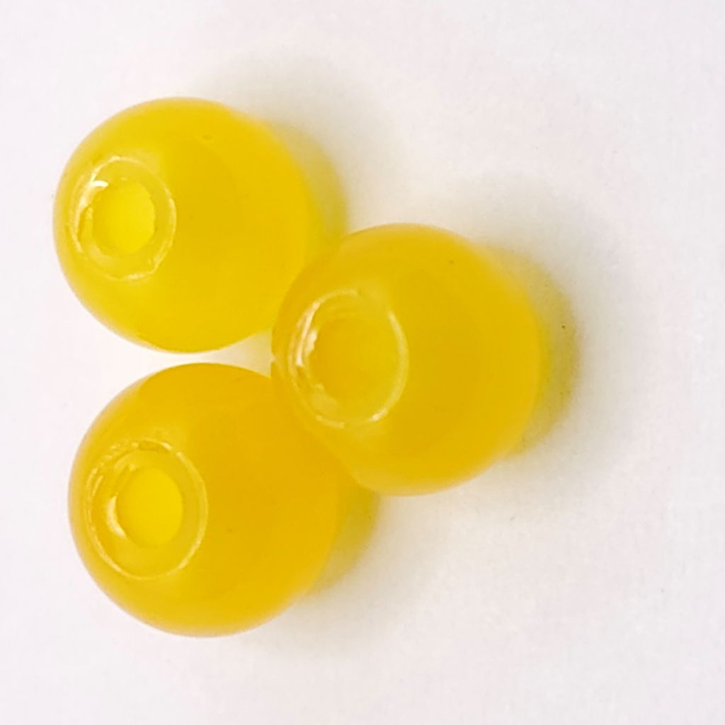 Three translucent yellow round beads with a hollow center, arranged on a plain white background.