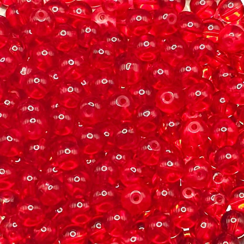 A close-up pile of small, round, translucent red craft beads with a glossy finish.
