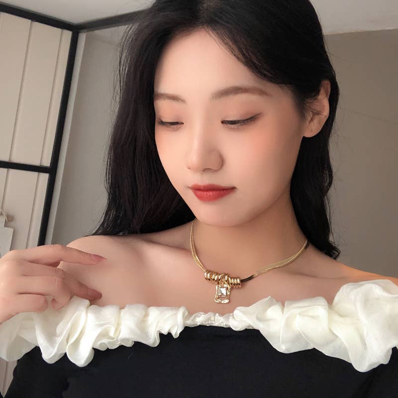 Woman wearing a gold necklace with a white top