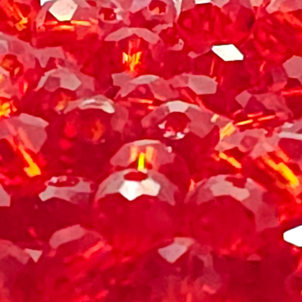A close-up of a circular product, likely a candle holder or decorative plate, covered in faceted red crystal beads on a white background.